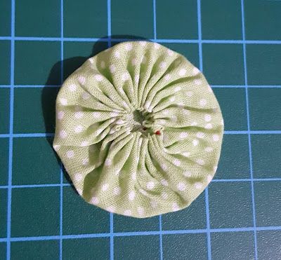 a green and white polka dot fabric hair scrunch on a blue cutting board