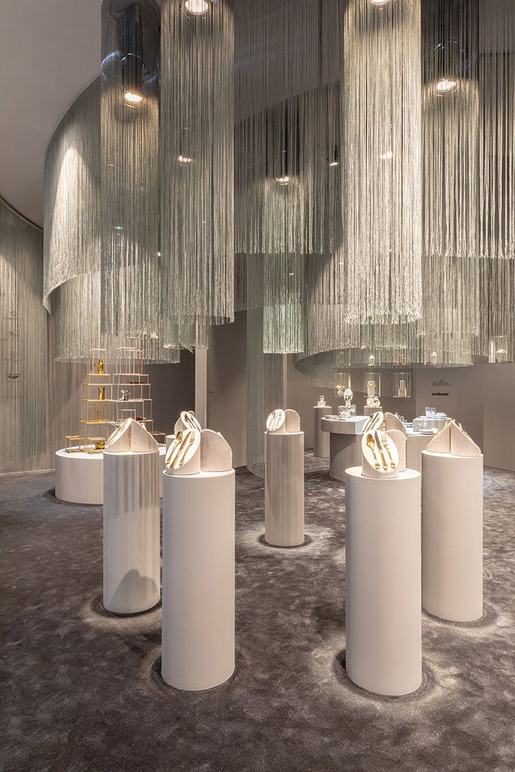 a room filled with tall white vases sitting on top of a carpet covered floor