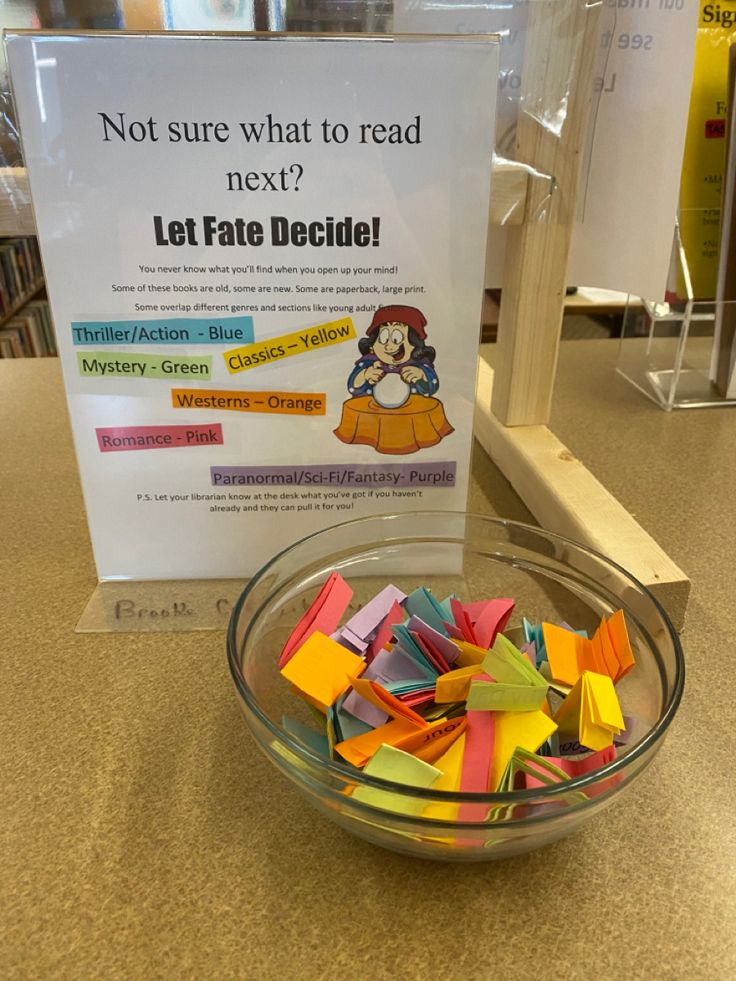 a glass bowl filled with lots of colorful pieces of paper next to a sign that says not sure what to read next