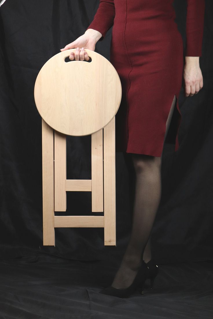 a woman in a red dress is standing next to a wooden stool with her legs crossed