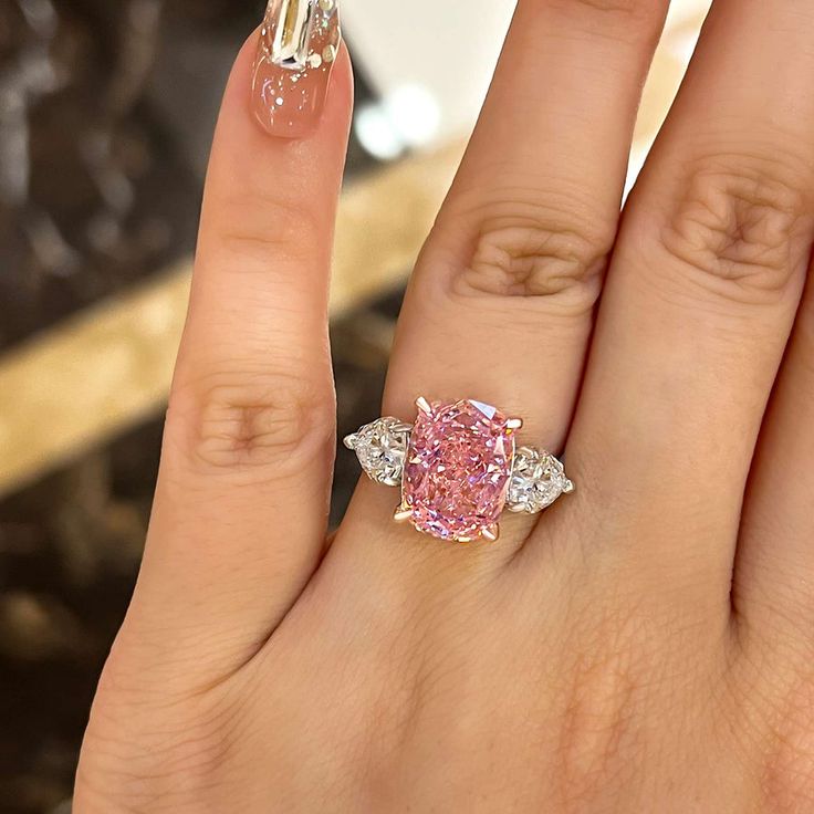 a woman's hand with a pink diamond ring on top of her left finger