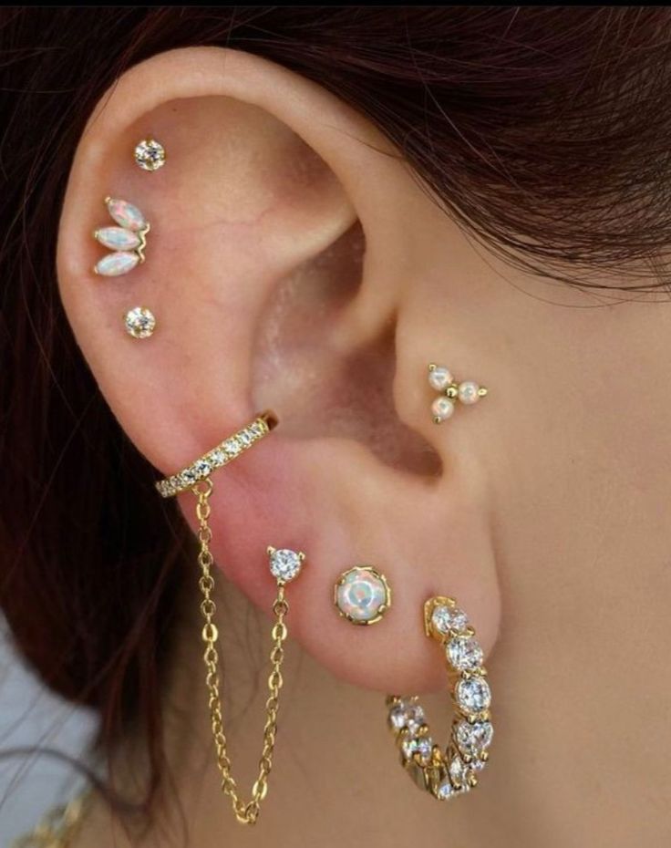 a woman wearing gold ear piercings with white flowers and chains attached to her ears