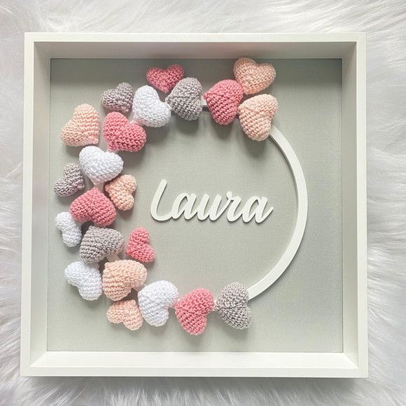 a white frame with pink and grey crocheted hearts on it that says,'laura '