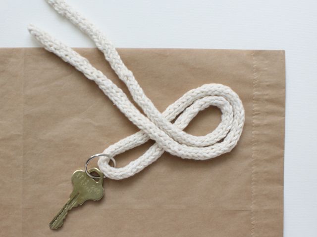 a white rope with a gold key on it sitting on top of a piece of brown paper