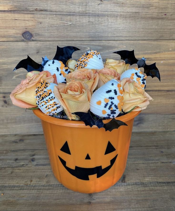 an orange bucket filled with halloween treats on top of a wooden floor