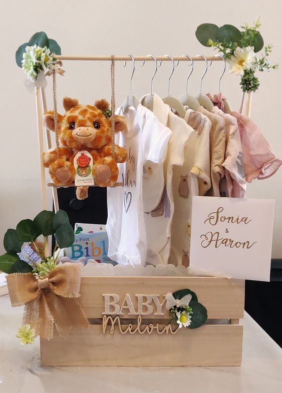 a teddy bear sitting on top of a wooden box filled with baby clothes and other items