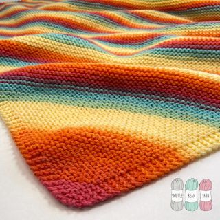 a crocheted blanket is laying on top of a white surface with the colors of rainbow