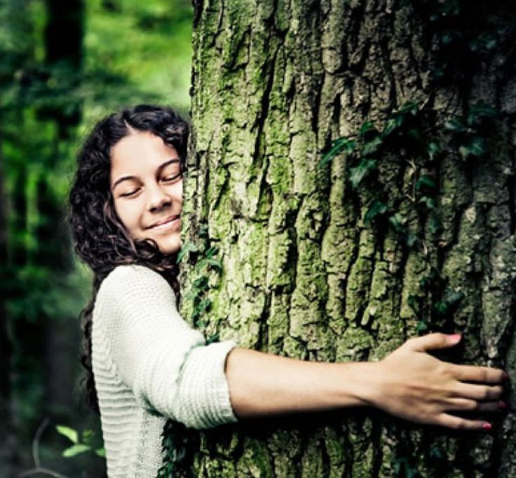 a woman hugging a tree in the woods