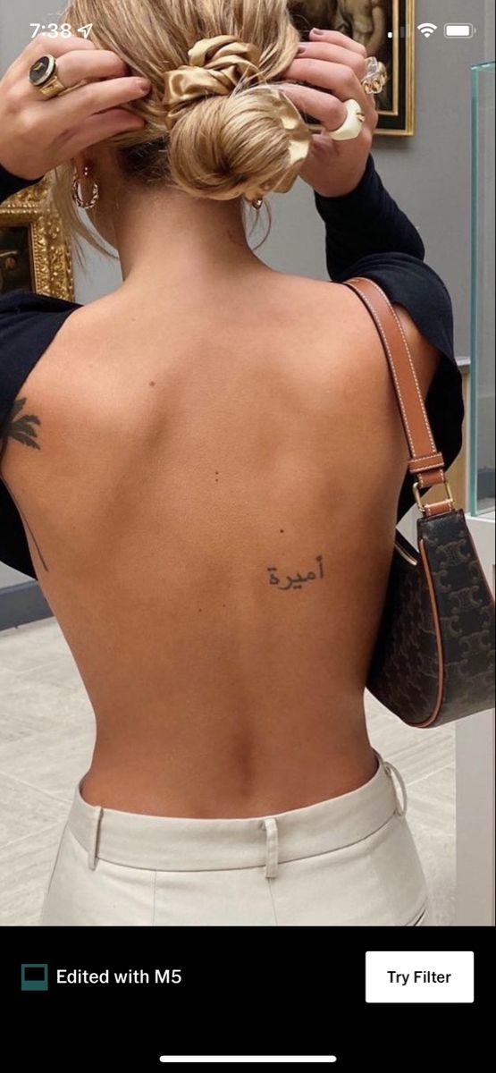 the back of a woman's head with tattoos on her upper and lower back