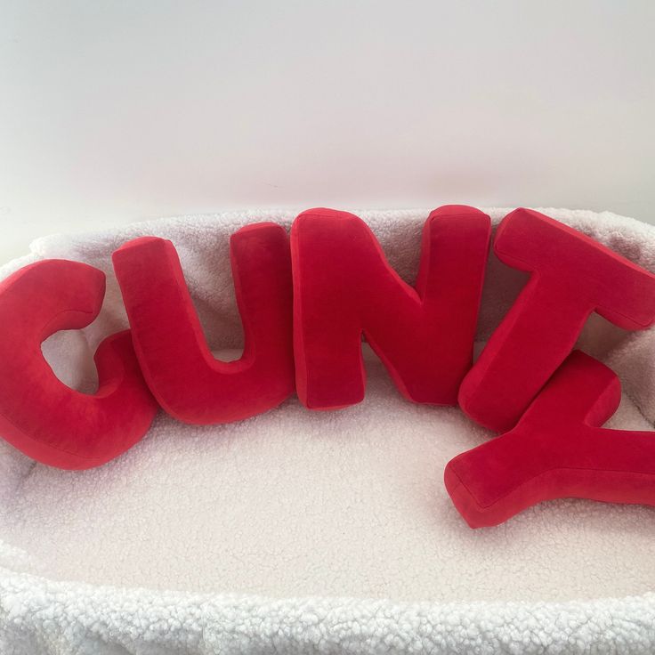 the word cune spelled out in red foam letters on a white blanketed surface