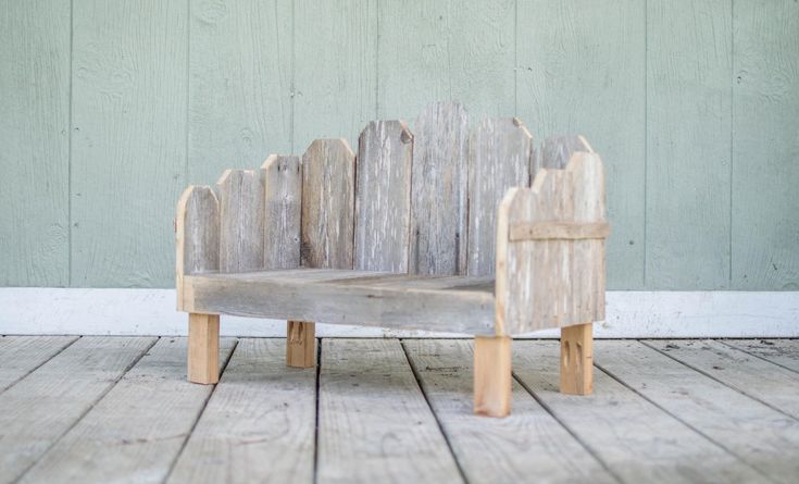 a small wooden chair sitting on top of a wooden floor next to a green wall