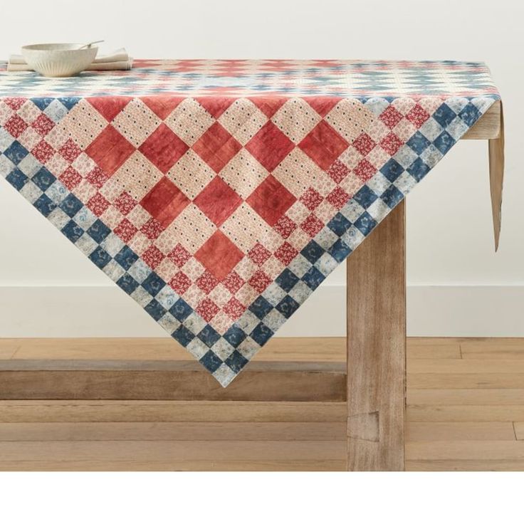 a red, white and blue quilted tablecloth on a wooden bench in front of a wall