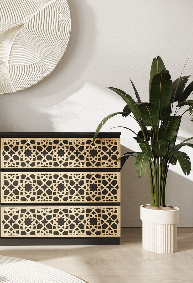 a plant in a white vase next to a wooden dresser with intricate carvings on it