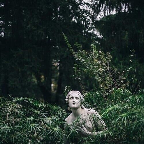 a statue sitting in the middle of tall grass