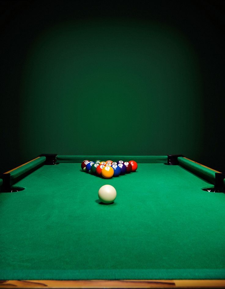 a pool table with a ball and cues resting on the green cloth in front of it