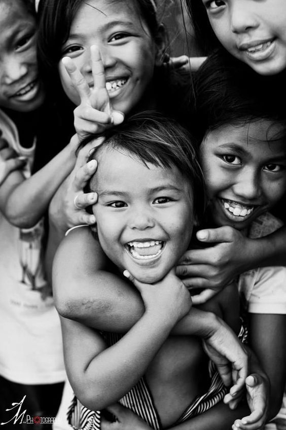 black and white photograph of young children smiling for the camera with their hands in the air