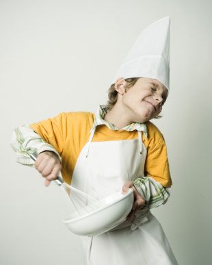 a young boy wearing an apron and holding a bowl