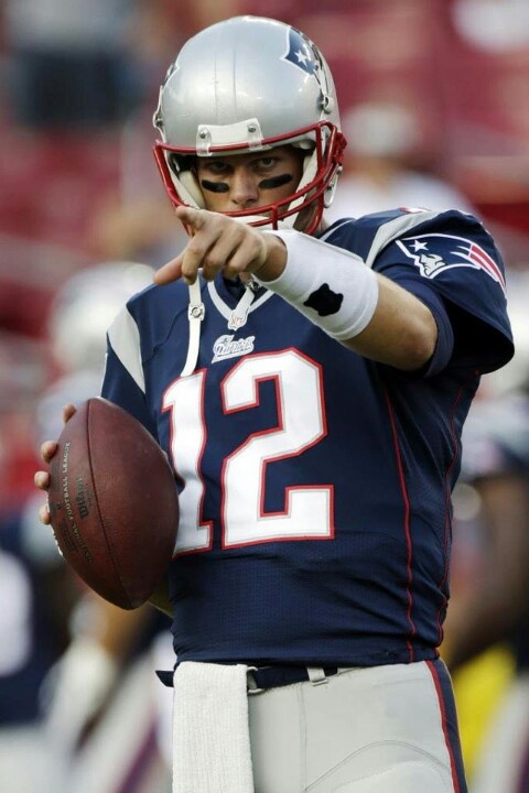 a football player holding a ball in his right hand and pointing to the sideline