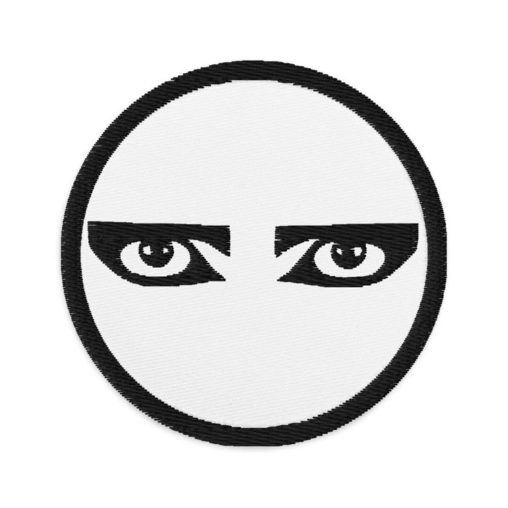 a white and black patch with an evil face in the center, surrounded by eyes