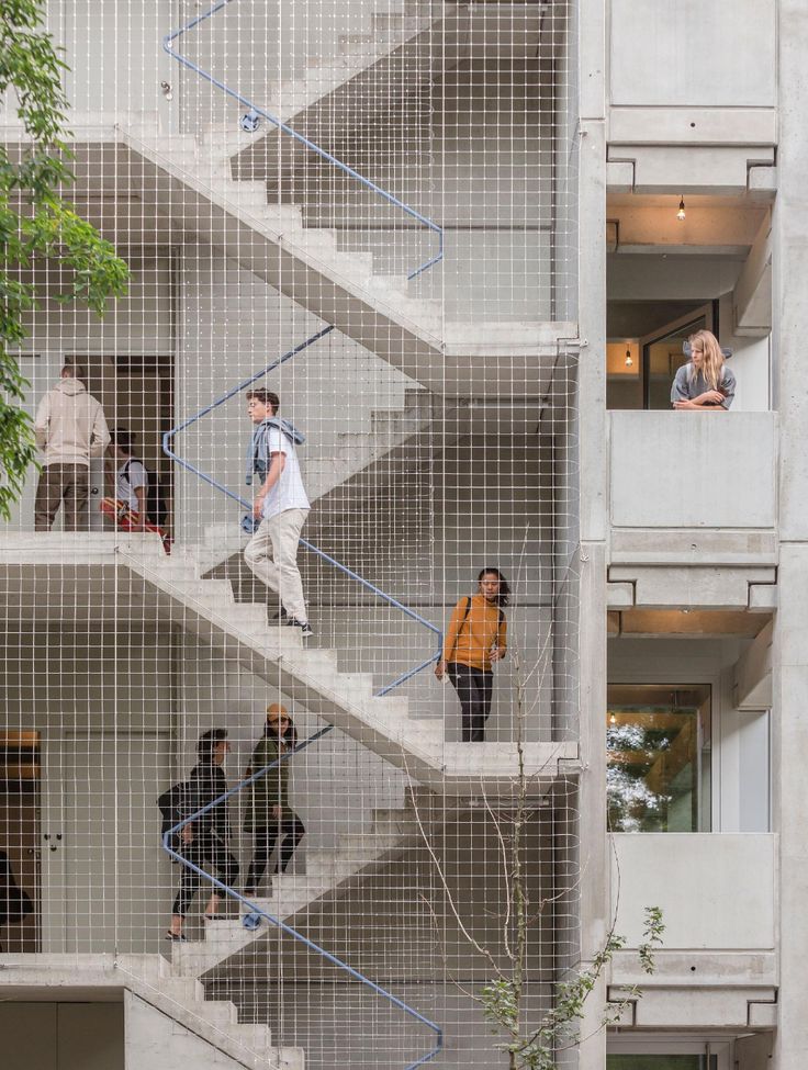 several people are walking up and down the stairs in an apartment building with metal mesh