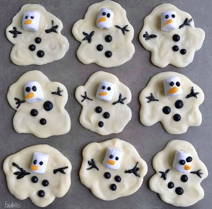 frosted snowman cookies are arranged on a baking sheet