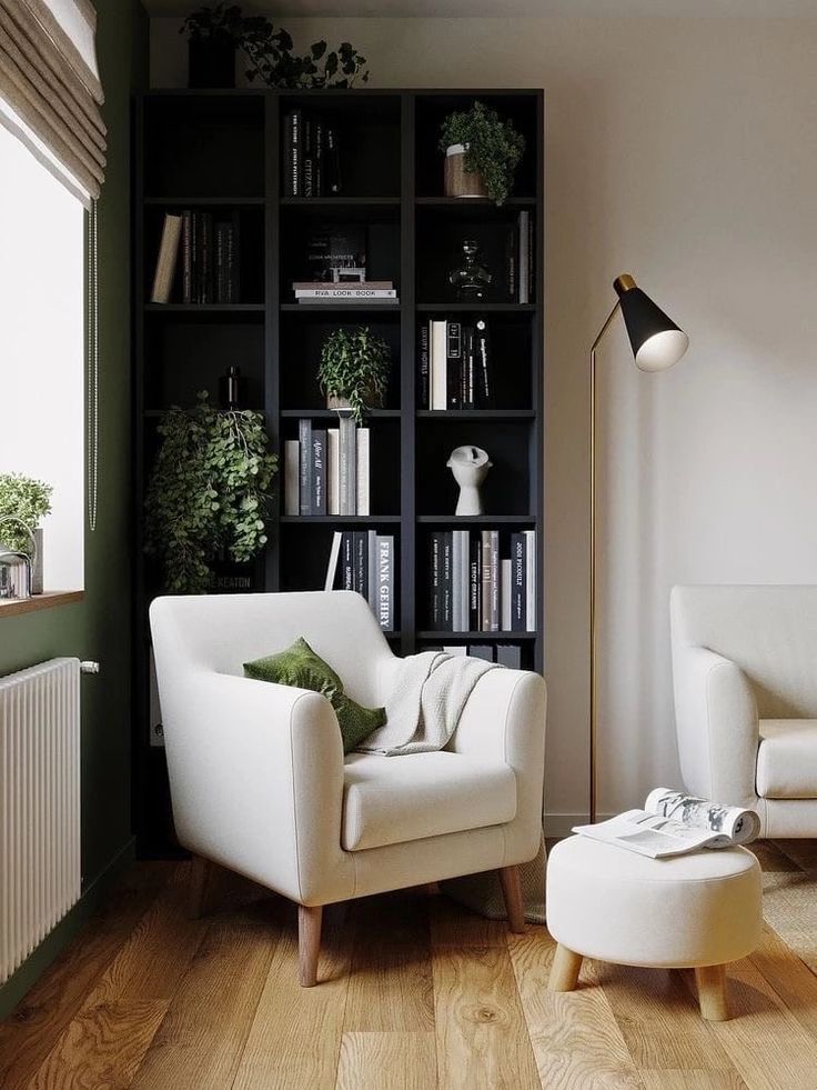 a living room filled with furniture and bookshelves next to a white chair in front of a window