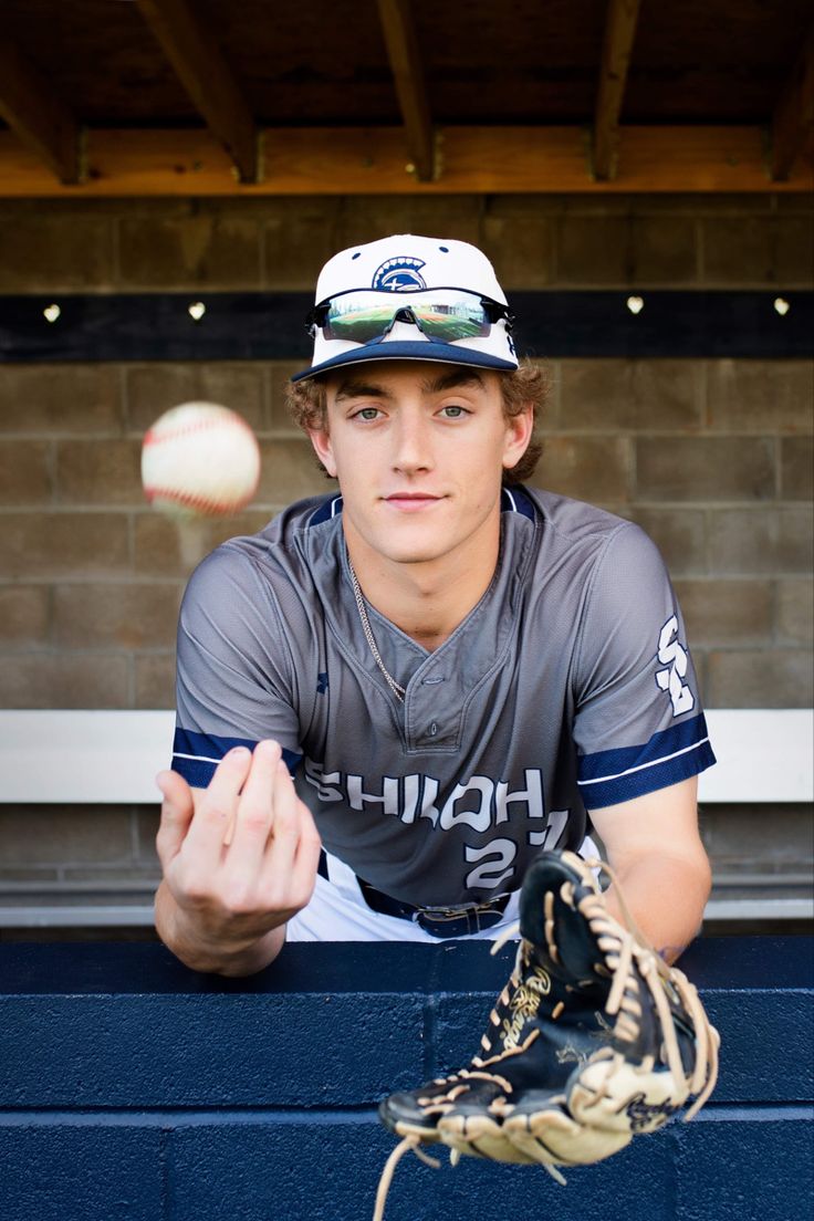 a baseball player is throwing a ball in the dugout while wearing a catchers mitt