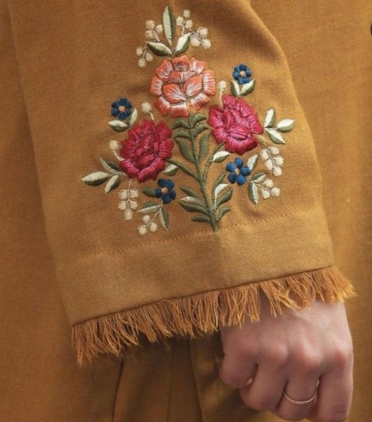 a close up of a person's hand with a flower embroidered on the jacket