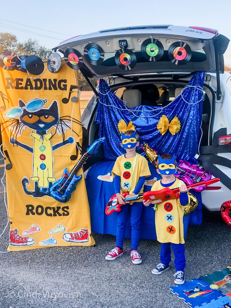 two children are standing in front of a car with decorations on the hood and back