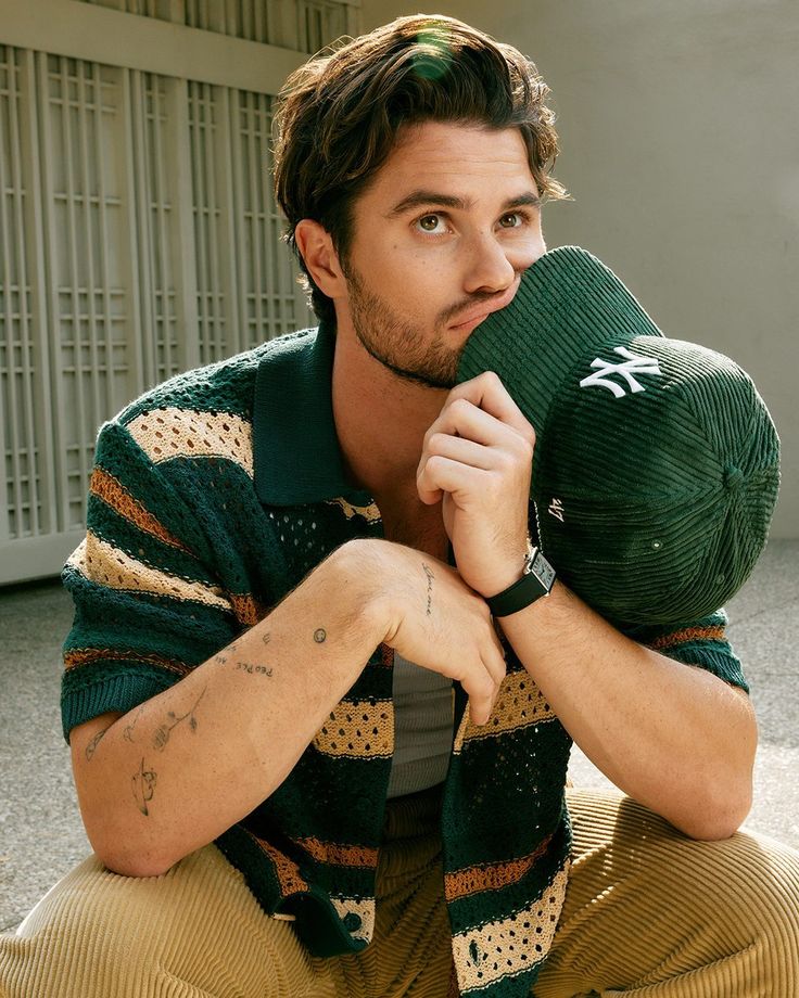 a man sitting on the ground with his hands under his face and holding a pillow