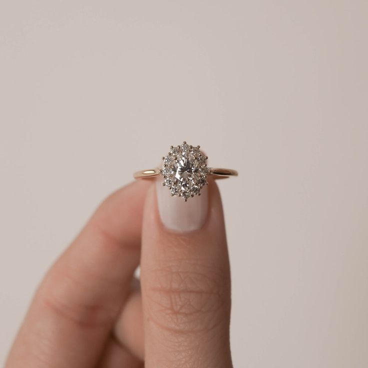 a woman's hand holding an engagement ring with a diamond in the center and two diamonds on each side