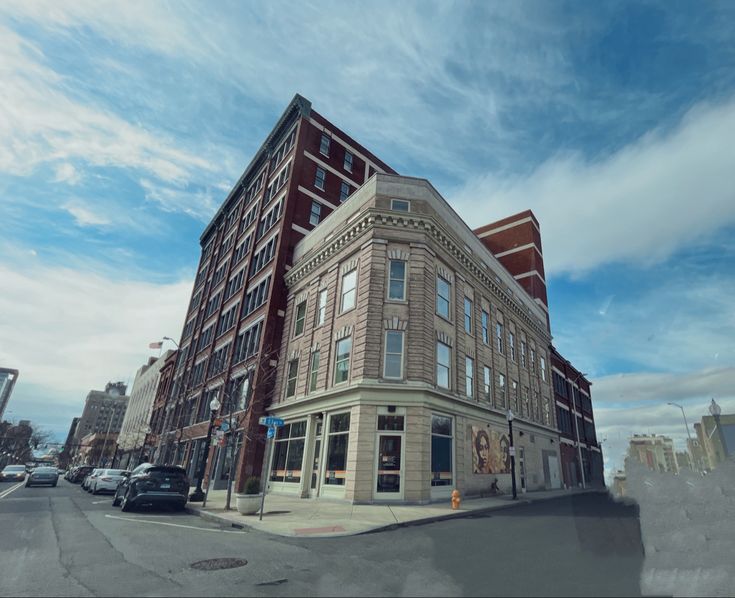 an old brick building on the corner of a street with cars parked in front of it