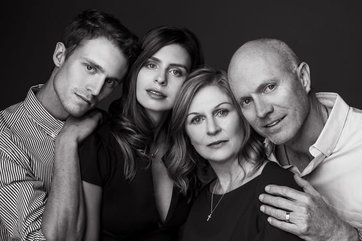 four people are posing for a black and white photo with their arms around each other