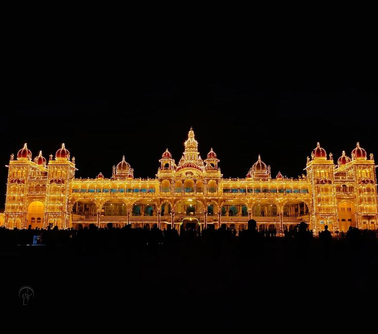 an ornate building lit up at night with lights on it's front and sides