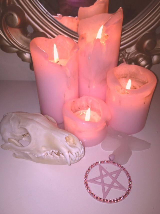 some candles are sitting on a table next to a pentagramil and a skull