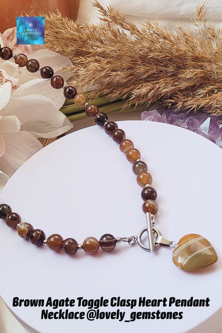 a brown agate bead necklace with heart shaped stone beads on a white plate