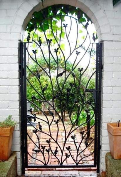 an iron gate with potted plants on either side