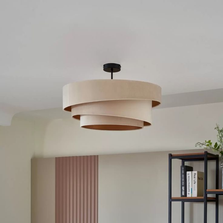 a living room with a round light fixture hanging from the ceiling and bookshelves