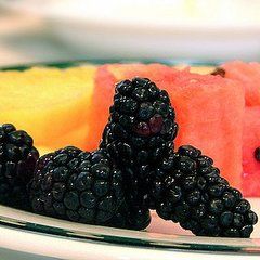 some blackberries, watermelon and pineapple on a plate