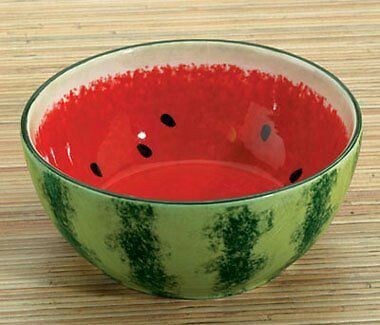 a watermelon bowl on a wooden table with red liquid in the bottom and black dots