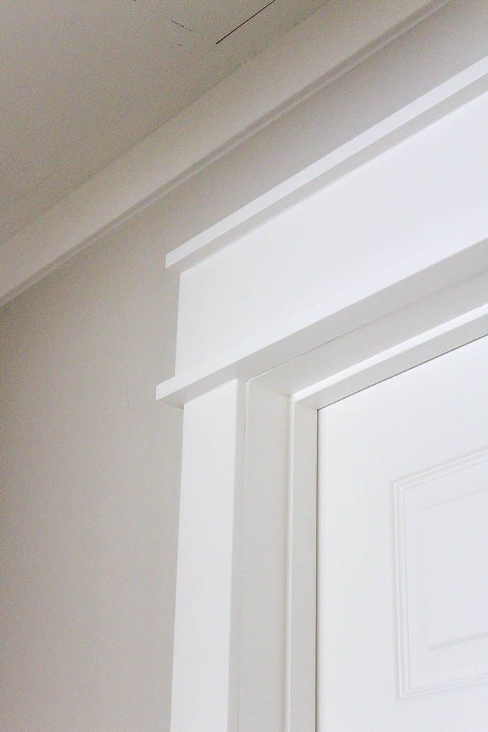 the corner of a white door with a small window in it's center area