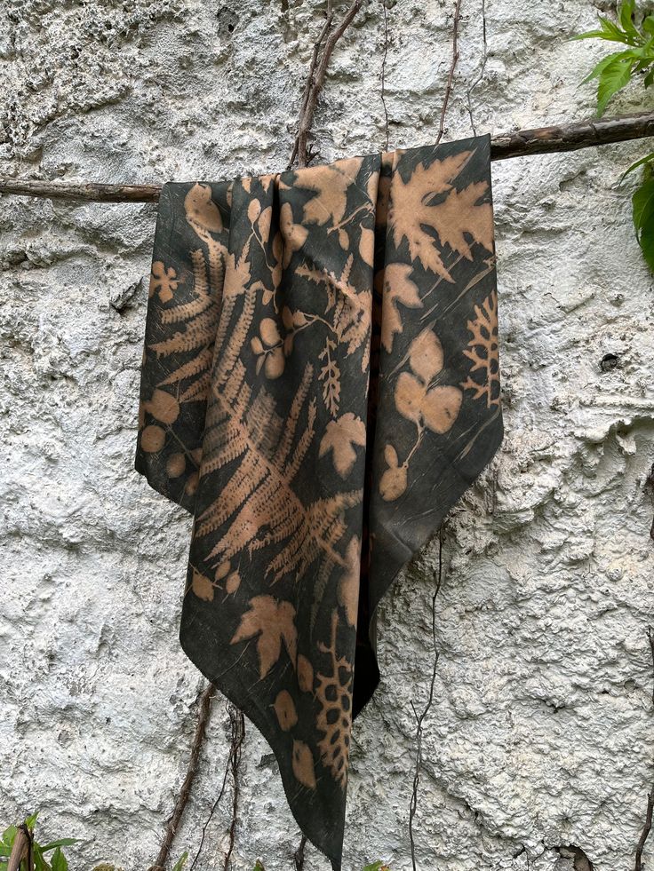 a towel hanging on a clothes line next to a stone wall with vines and leaves