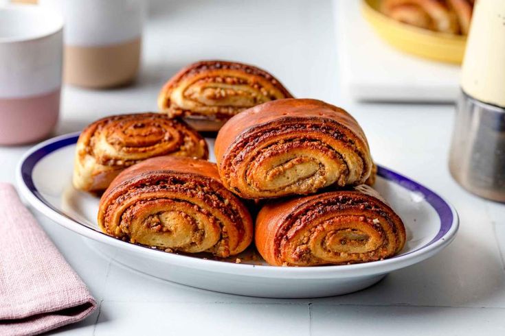 a white plate topped with cinnamon rolls on top of a table next to a pink napkin