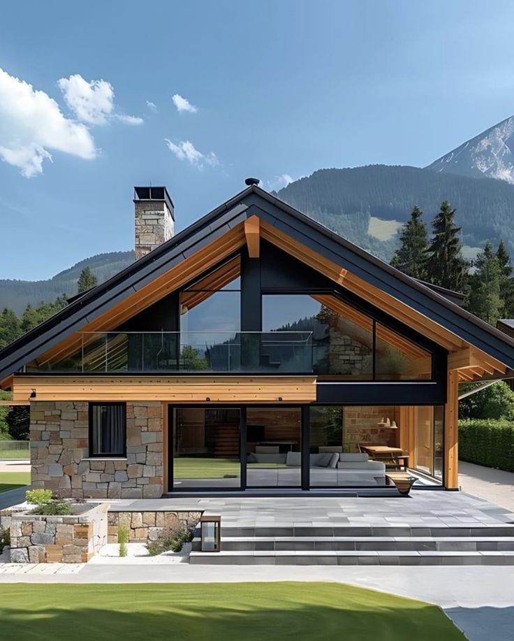 a house with a large patio and stone steps leading up to the front door is surrounded by mountains