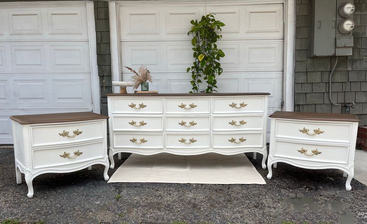 three white dressers with brown top sitting in front of a garage