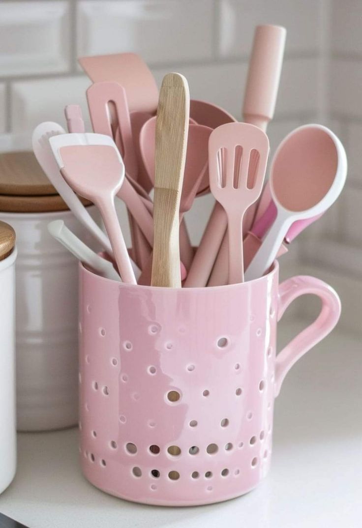 a pink mug filled with utensils and spoons