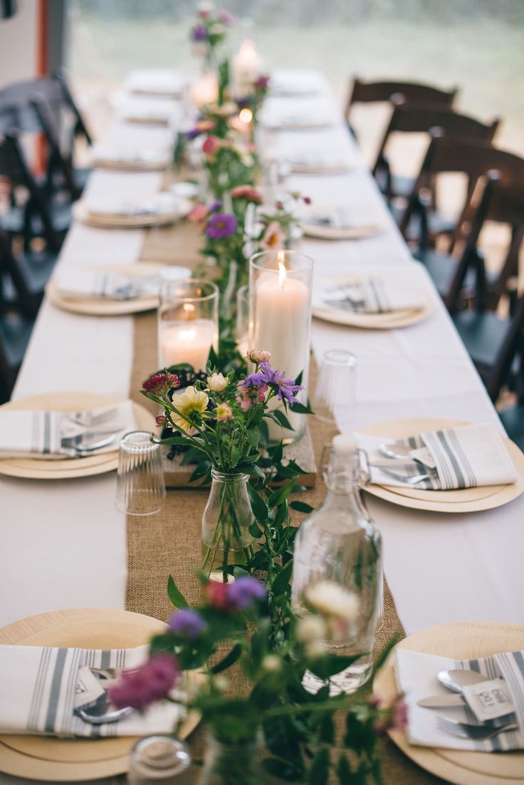 a long table set with place settings and flowers