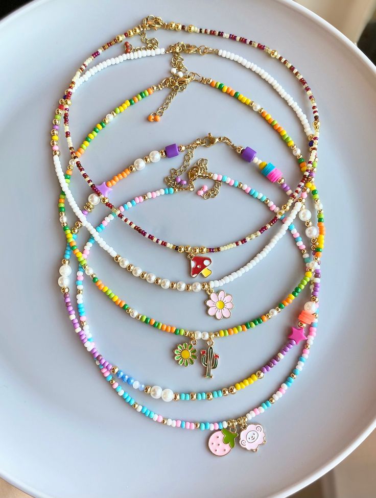 a white plate topped with lots of different colored beads and necklaces on top of it