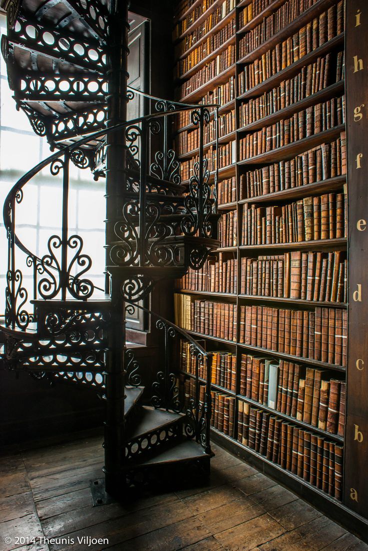 a spiral staircase in front of a bookshelf filled with lots of bookcases