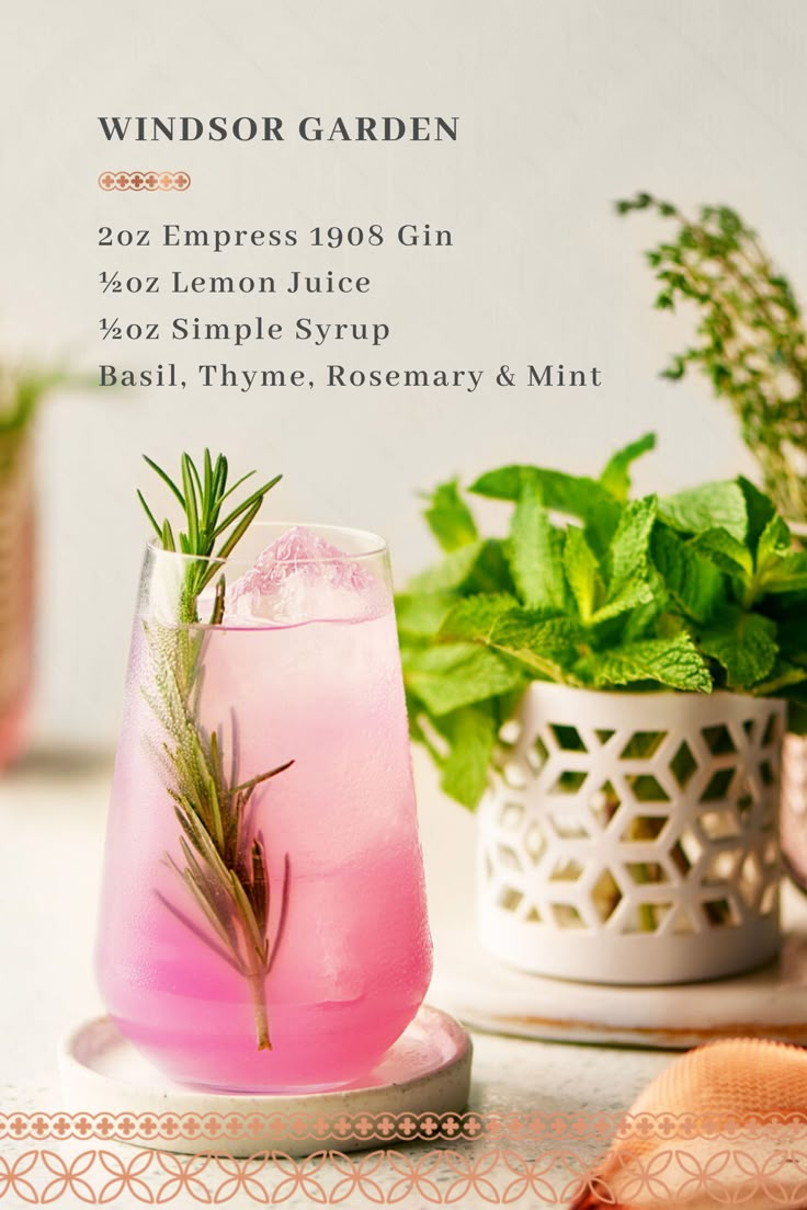 a pink drink sitting on top of a table next to a potted plant